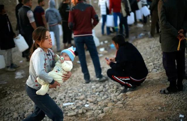 A displaced Iraqi girl, who fled the Islamic State stronghold of Mosul, holds a baby at Khazer camp, Iraq November 24, 2016. (Photo by Mohammed Salem/Reuters)