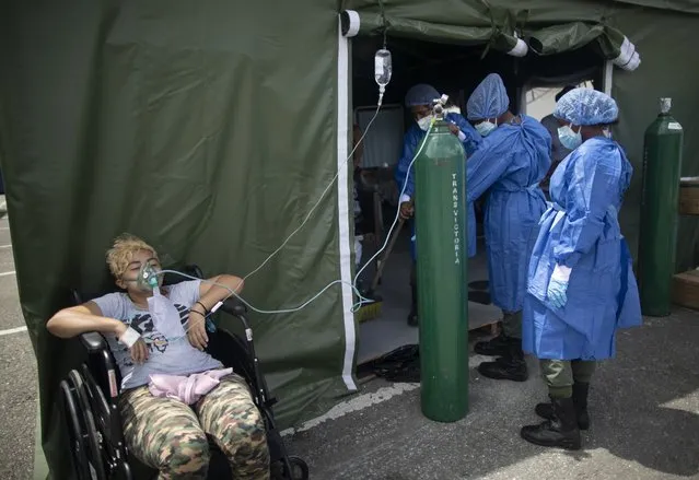 A woman who suffers from COVID-19 receives oxygen at a field hospital set up in the parking lot of the Poliedro de Caracas auditorium, in Venezuela, Sunday, March 21, 2021. (Photo by Ariana Cubillos/AP Photo)