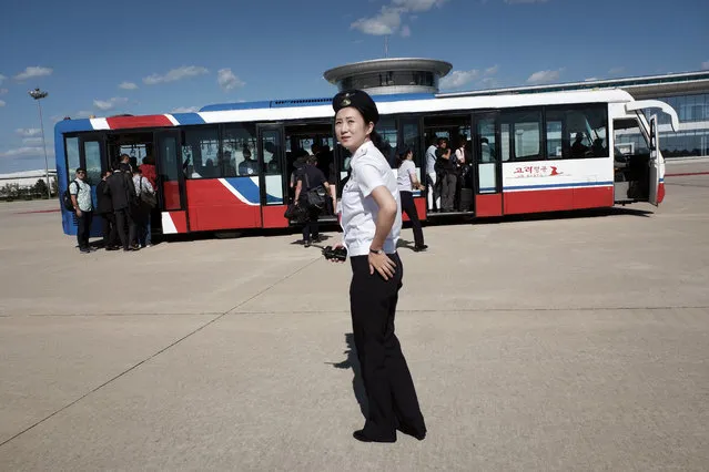 A North Korean airport worker guides passengers, including foreign journalists invited for the 70th anniversary of North Korea's founding day, onto buses after arriving on a plane at the airport in Pyongyang, North Korea, Friday, September 7, 2018. (Photo by Kin Cheung/AP Photo)