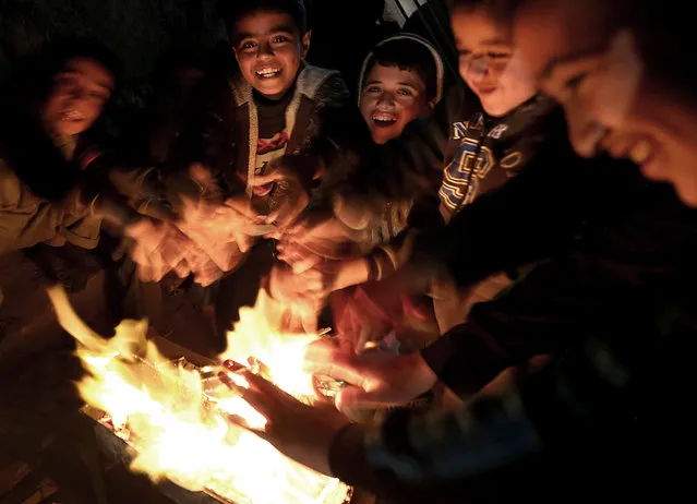 A picture made available on 12 January 2016 shows Palestinian refugee boys warming up in front of a fire during a power outage as they endure the cold weather in Al Shateaa camp, in the west of Gaza City, Gaza Strip, 08 January 2016. Residents of Gaza, home to 1.8 million people, experience some 12 hours of electricity outage per day. (Photo by Mohammed Saber/EPA)