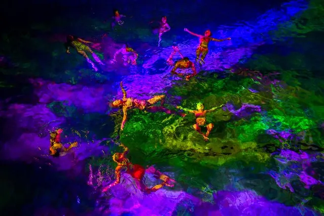 People swim in the lighted water of the Hirschengraben indoor swimming pool in Bern during an artistic performance by Swiss visual artist Pipilotti Rist and World Wide Fund for Nature (WWF) Switzerland non-governmental organization to denounce the disappearance of corals due to the warming and the acidification of the ocean on October 7, 2018. (Photo by Fabrice Coffrini/AFP Photo)