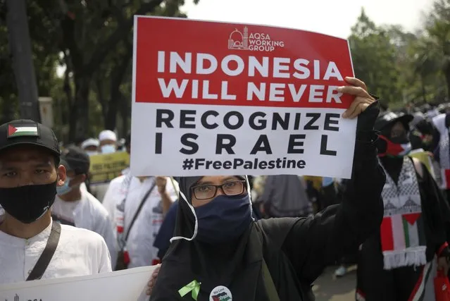 A Muslim woman holds up a poster during a rally against Israel's attacks on Gaza, outside the U.S. Embassy in Jakarta, Indonesia, Friday, May 21, 2021. (Photo by Dita Alangkara/AP Photo)