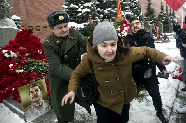 A man in a Soviet army uniform, left, pushes away out a woman, who threw flowers at the monument signifying Soviet dictator Joseph Stalin's grave near the Kremlin wall and shouted words that Stalin killed her family and she hated him, as other people come to mark the anniversary of Stalin's birth in Moscow's Red Square, Russia, Wednesday, December 21, 2016. (Photo by Pavel Golovkin/AP Photo)