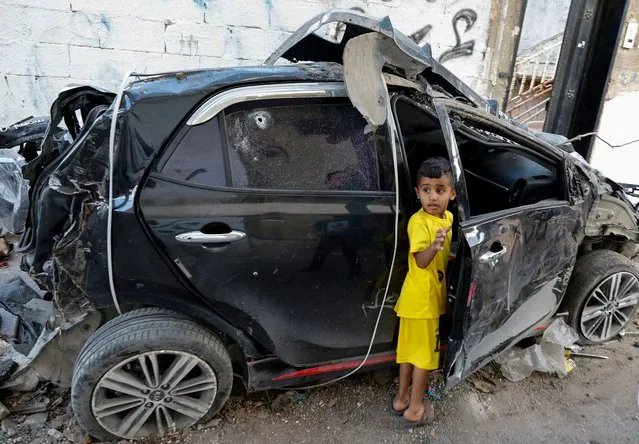 A Palestinian boy stands next to a damaged car following an Israeli raid in Tulkarm in the Israeli-occupied West Bank on October 20, 2023. (Photo by Raneen Sawafta/Reuters)