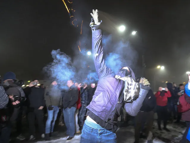 A protester throws a smoke grenade during a rally in front of the embassy of Russia in Kiev, Ukraine, Sunday, November 25, 2018. Russia's coast guard opened fire on and seized three of Ukraine's vessels Sunday, wounding two crew members, after a tense standoff in the Black Sea near the Crimean Peninsula, the Ukrainian navy said. (Photo by Efrem Lukatsky/AP Photo)