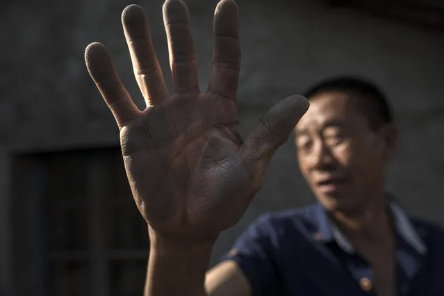 Lyu Shengwen, 55, shows the graphite dust he collected on the side of his house, which he cleaned the day before, in the town of Mashan, China on May 28, 2016. Shengwen lives next door to a graphite factory owned and operated by Aoyu and graphite laden trucks ply the road in front of his home. (Photo by Michael Robinson Chavez/The Washington Post)