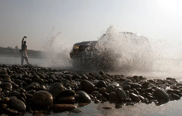 A photographer takes pictures as an SUV takes part in the Indus river water cross race in Swabi, outside Peshawar, Pakistan December 18, 2016. (Photo by Fayaz Aziz/Reuters)