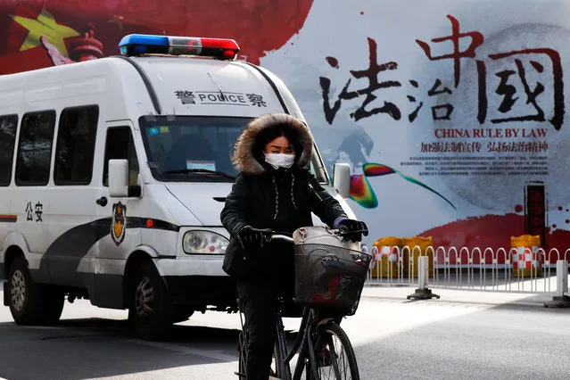 A woman rides a bicycle in front of a police van as they pass a Chinese government's propaganda billboard that reads “China Rule By Law” on a street in Beijing, Wednesday, December 28, 2016. Infuriated by a decision by Beijing prosecutors to drop charges in a high-profile police brutality case, university alumni circles across China mobilized online this week with petition drives, posing to China's government an unusual challenge with its white-collar makeup and swiftly expanding nationwide reach. (Photo by Andy Wong/AP Photo)