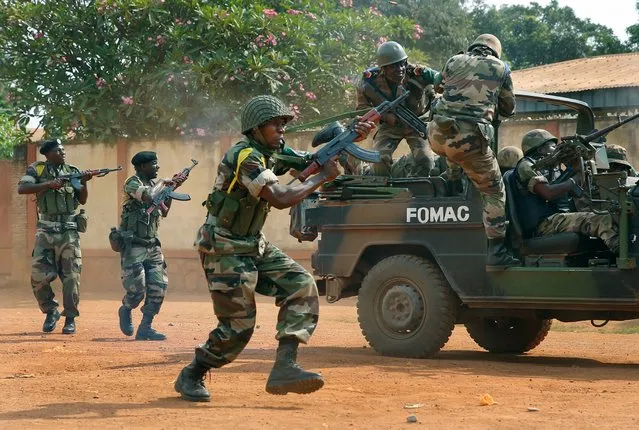 FOMAC troops, regional peacekeepers, fire their guns as they evacuate Muslim clerics from the St. Jacques Church in Bangui, Central African Republic on Thursday, December 12, 2013. An angry crowd had gathered outside the church following rumors that a Seleka general was inside. The Seleka is an alliance of mostly Muslim rebels from the north who tossed out the country's Christian president in a coup. (Photo by Jerome Delay/AP Photo)
