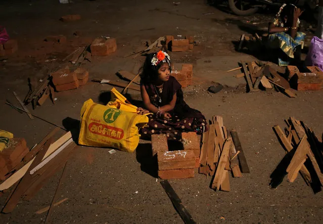 A girl sits in between brick stoves before devotees prepare rice dishes to offer to the Hindu sun god during Pongal celebrations early morning on a roadside in Mumbai, January 15, 2019. (Photo by Francis Mascarenhas/Reuters)