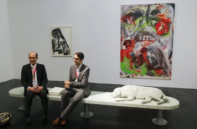 Gallerists sit on a concrete bench showing a sleeping dog by Italian artist Alberto Garutti at the Art Cologne 2015 fair in Cologne April 15, 2015. The bench is part of a contemporary art project of the little Italian municipality of Trivero, northeast of Turin in the Piedmont region, portraying dogs that belong to Trivero families. (Photo by Wolfgang Rattay/Reuters)