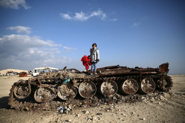 11-year-old Syrian girl Rawan poses on a destroyed tank with her stuffed bear near the village of Yazi Bagh, about six kilometres from the Bab al-Salamah border crossing between Syria and Turkey in the north of Aleppo province, on February 19, 2019. (Photo by Nazeer Al-Khatib/AFP Photo)