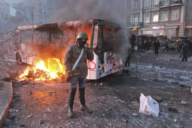 A pro-European integration protester stands in front of a burning police bus during a rally near government administration buildings in Kiev January 20, 2014. Protesters clashed with riot police in the Ukrainian capital on Sunday after tough anti-protest legislation, which the political opposition says paves the way for a police state, was rushed through parliament last week. (Photo by Valentyn Ogirenko/Reuters)