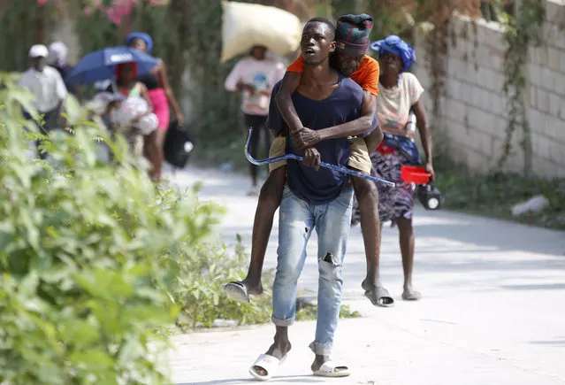 A resident carries an elderly man on his back as they flee their home to avoid clashes between armed gangs in the Pernier district of Petion-Ville, Haiti, Wednesday, January 31, 2024. (Photo by Odelyn Joseph/AP Photo)