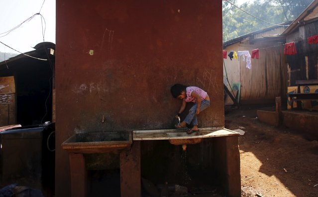 A Guarani Indian girl washes her foot in the village of Pyau at Jaragua district, in Sao Paulo April 28, 2015. (Photo by Nacho Doce/Reuters)