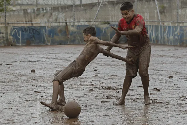 Youths playing soccer slip on a court covered in mud brought by flooding in Sao Paulo, Brazil, Monday, March 11, 2019. According to The Sao Paulo state fire department, heavy rains have caused the deaths of at least 11 people in and around Brazil's largest city, including a 1-year-old baby. (Photo by Andre Penner/AP Photo)