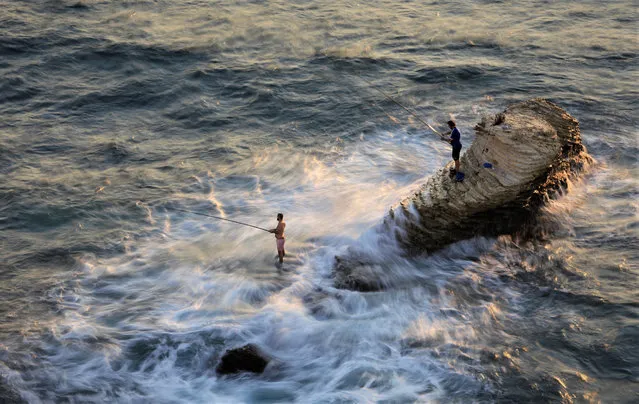 Photo taken on October 3, 2021 shows people fishing on a reef near the coast of the Mediterranean Sea in Beirut, Lebanon. (Photo by Xinhua News Agency/Rex Features/Shutterstock)