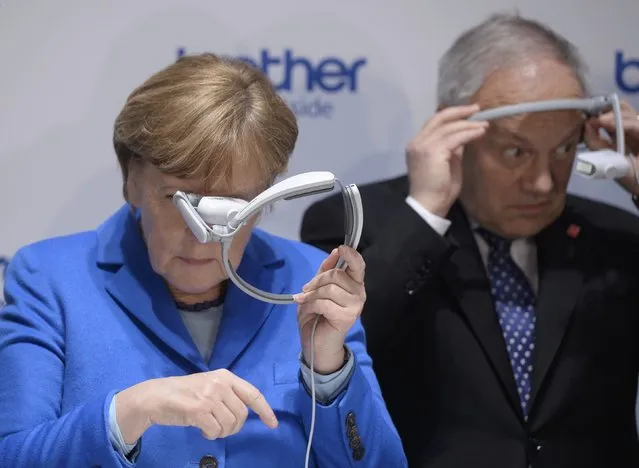 German Chancellor Angela Merkel and Swiss President Johann Schneider-Ammann (R) look at head-mounted display units on the Brother International exhibition stand during a media tour of the world's biggest computer and software fair, CeBit, in Hanover, Germany, March 15, 2016. (Photo by Nigel Treblin/Reuters)