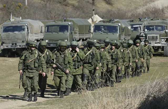 Military personnel, believed to be Russian servicemen, walk outside the territory of a Ukrainian military unit in the village of Perevalnoye outside Simferopol March 3, 2014. Ukraine mobilised for war on Sunday and Washington threatened to isolate Russia economically after President Vladimir Putin declared he had the right to invade his neighbour in Moscow's biggest confrontation with the West since the Cold War. (Photo by David Mdzinarishvili/Reuters)