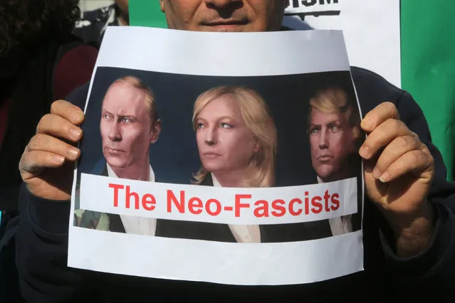 A protester holds a banner during a protest against the visit of Marine Le Pen, French National Front (FN) political party leader and candidate for the French 2017 presidential elections, to Lebanon, after she was scheduled to hold a press conference, in Beirut, Lebanon February 21, 2017. The banner depicts (L-R) Russian President Vladimir Putin, Marine Le Pen, French National Front (FN) political party leader and candidate for French 2017 presidential election, and U.S. President Donald Trump. (Photo by Aziz Taher/Reuters)