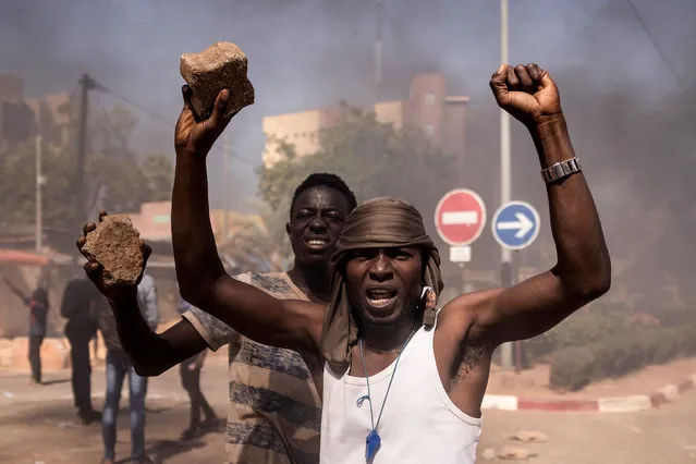 Protestors hold cobblestones during a demonstration in Ouagadougou on November 27, 2021. Anti-riot police fired tear gas to prevent the demonstrators from gathering in a square in the centre of Ouagadougou, where substantial police and security forces were deployed and all shops closed. (Photo by Olympia de Maismont/AFP Photo)