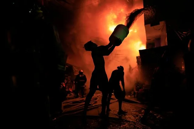 Firefighters and residents try to extinguish a fire in a residential district of Las Pinas city, Metro Manila, Philippines, 01 April 2024. According to a report by the Philippines Bureau of Fire Protection (BFP), fire incidents between January and March are higher by 24 percent over the same period in 2023. Firefighters experienced a sharp increase in calls from households due to power overload and overheating of electric fans from non-stop usage, leading to fires. (Photo by Francis R Malasig/EPA/EFE)