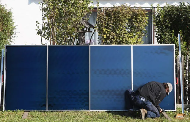 Workers install solar power modules for producing heat on the roof of a house