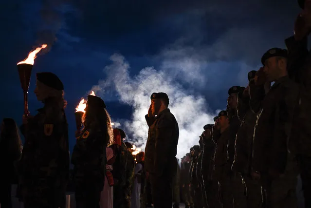Kosovo Albanians dressed in military costumes carry torches and salute during a bonfire ceremony, marking the 19th anniversary of the killing of Kosovo Liberation Army (KLA) founding member and commander Adem Jashari, on March 7, 2017 in Prekaz. Jashari was among 45 members of family killed by Serb security forces in the village of Prekaz ,west of Kosovo capital Pristina, sparking a full-blown rebel insurgency. (Photo by Armend Nimani/AFP Photo)
