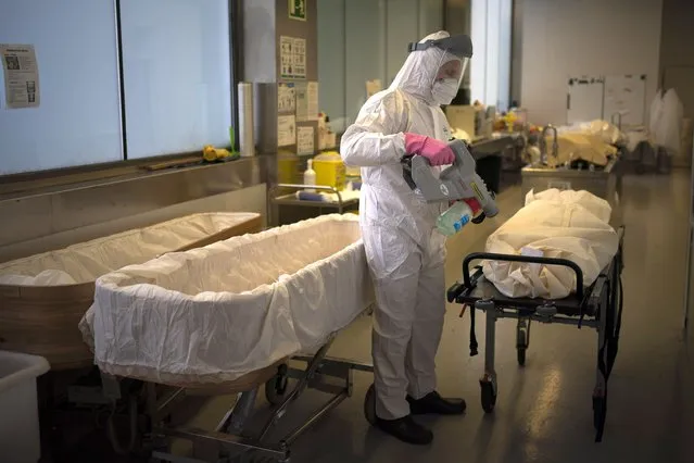A mortuary worker disinfests the body of a person who died of COVID-19 ahead of a funeral at Memora mortuary in Girona, Spain, Thursday, February 4, 2021. Spain's health ministry said Wednesday that the southern European nation has surpassed 60,000 fatalities from COVID-19. The ministry reported 565 new deaths in the previous 24 hours, taking the total death count since the start of pandemic to 60,370. (Photo by Emilio Morenatti/AP Photo)