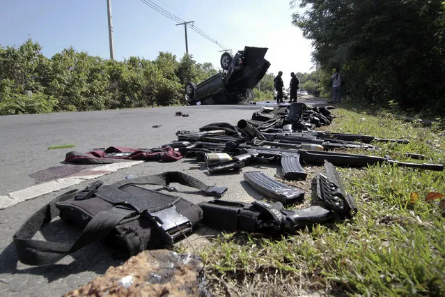 Gear and weapons of victims are placed by the road as security forces inspect the site of a bomb attack on police in the troubled southern province of Narathiwat March 30, 2014. Two policemen were killed and three wounded in a roadside bomb attack as they were traveling to provide security to the polling stations for Sunday's Senate elections, local media reported. (Photo by Surapan Boonthanom/Reuters)