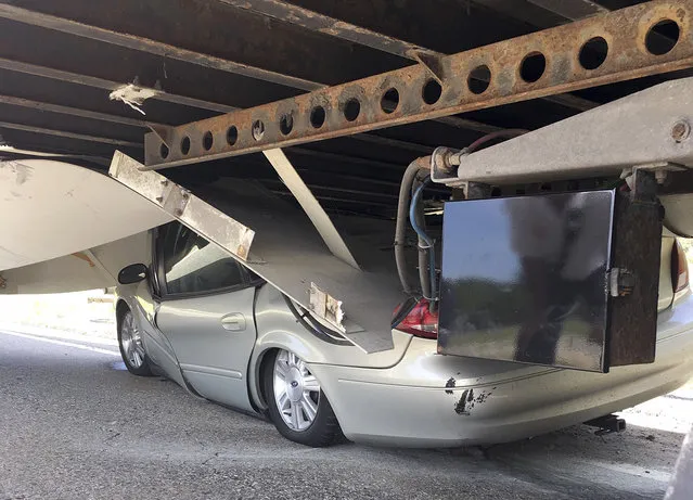 In this Tuesday, July 16, 2019 photo photo released by the Uxbridge Fire Department on its Facebook page, a car sits wedged under a tractor-trailer on Route 146 in Uxbridge, Mass. The motorist, whose name wasn't made public, climbed out of the driver's side door of the crushed car and wasn't seriously hurt. (Photo by Uxbridge Fire Department via AP Photo)