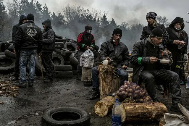 Pro-Russian protesters eat beside a barricade at one of the entrances to Slovyansk, Ukraine, on April 13, 2014. A Ukrainian official said special forces on Sunday evicted gunmen from the Slovyansk Police Headquarters, but local residents and men at barricades denied that Ukrainian forces had even entered the town.  (Photo by Mauricio Lima/The New York Times)