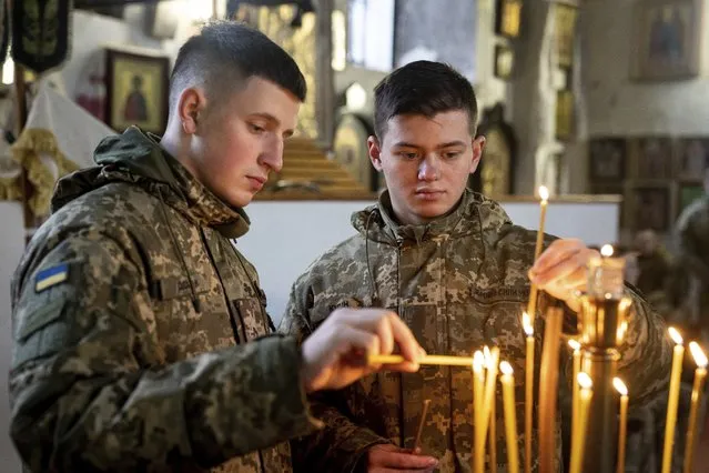Ukrainian Military Air Force University cadets light candles during a monthly memorial service for soldiers who were killed during the fighting against Russia-backed separatists in eastern Ukraine, in Kharkiv, Ukraine, Thursday, February 3, 2022. Russia maintains it has no intention to attack its neighbor, but demands that NATO won't expand to Ukraine and other ex-Soviet nations or deploy weapons there. It also wants the alliance to roll back its deployments to Eastern Europe. (Photo by Evgeniy Maloletka/AP Photo)