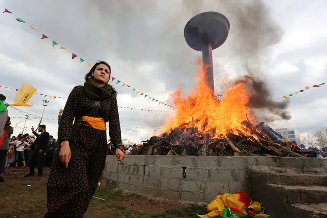 A woman walks past a bonfire during a gathering celebrating Newroz in the Kurdish-dominated southeastern city of Diyarbakir, Turkey on March 21, 2017. (Photo by Sertac Kayar/Reuters)