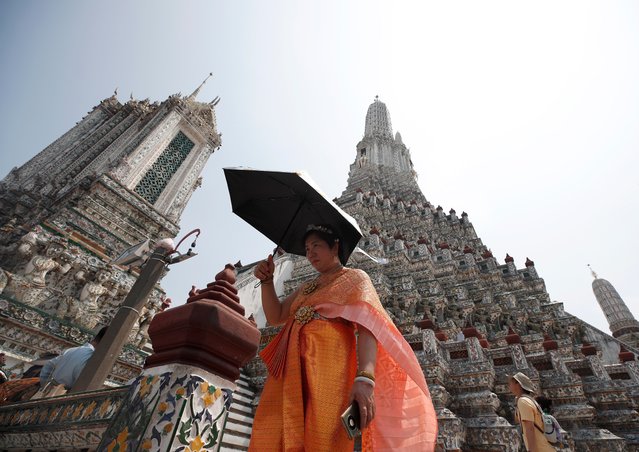 A tourist dressed in Thai traditional rented costumes uses an umbrella to protect herself from sunlight amid hot weather at the Temple of Dawn, or Wat Arun, in Bangkok, Thailand, 06 May 2024. Thailand is facing a severe heatwave as the Thai Meteorological Department warned about the extremely hot weather with temperatures soaring to record highs over 44 degrees Celsius in some areas and advised the public to avoid prolonged outdoor activities from a highly dangerous heat level index that directly hazardously affects health conditions. A total of 38 people have been reported dead of heatstroke in Thailand from February to May 2024, according to Dr Atthapol Kaewsamrit, Deputy Director-General of the Health Department. The United Nations revealed in its recent report that Asia was identified as the global disaster center and anticipated to be significantly affected by climate related disruptions such as extreme temperatures, severe heatwave, floods, storms and melting glaciers. (Photo by Rungroj Yongrit/EPA/EFE)