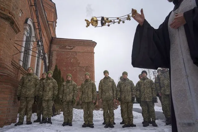 An Orthodox priest blesses Ukrainian Military Air Force University cadets after a monthly memorial service for soldiers who were killed during the fighting against Russia-backed separatists in eastern Ukraine, in Kharkiv, Ukraine, Thursday, February 3, 2022. Russia maintains it has no intention to attack its neighbor, but demands that NATO won't expand to Ukraine and other ex-Soviet nations or deploy weapons there. It also wants the alliance to roll back its deployments to Eastern Europe. (Photo by Evgeniy Maloletka/AP Photo)