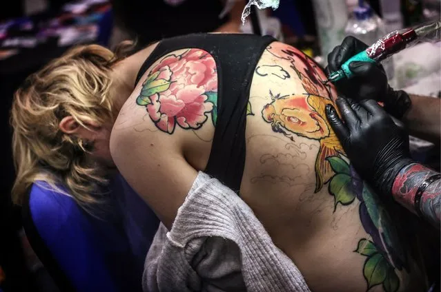 A tattoo artist applying ink on a girl' s back during the 2017 Moscow Tattoo Festival at Moscow' s Amber Plaza Shopping Center in Moscow, Russia on April 1, 2017. (Photo by Valery Sharifulin/TASS)