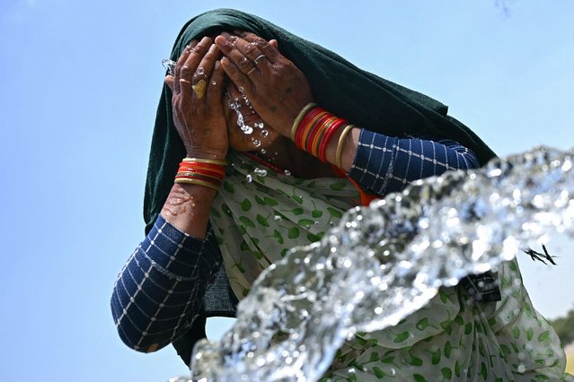 A woman washes her face with water to cool off during a hot summer day near the India Gate in New Delhi on June 17, 2024. (Photo by Money Sharma/AFP Photo)