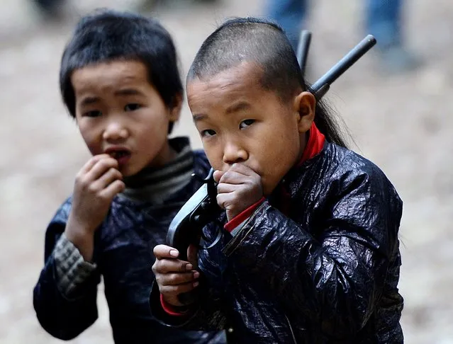 This photo taken on February 4, 2014 shows young members of the Miao minority group carrying replica guns in Biasha Village, Guizhou Province. The armaments in Biasha, a village tucked amid the wooded peaks of Guizhou province, are a reminder of an era of conflict between Beijing and the mountain tribes who still inhabit swathes of China's southwest. (Photo by Mark Ralston/AFP Photo)