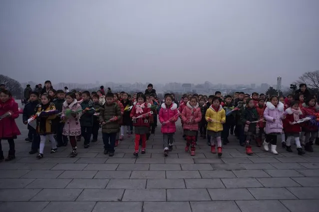 Children carry flowers as they visit the statues of late North Korean leaders Kim Il-Sung and Kim Jong-Il to pay their respects on the occasion of the 75th anniversary of the birth of Kim Jong-Il, at Mansudae hill in Pyongyang on February 16, 2017. North Korea marks Kim Jong-Il's February 16 birthday as the “Day of the Shining Star”, although accounts differ as to where and when he was born. (Photo by Ed Jones/AFP Photo)
