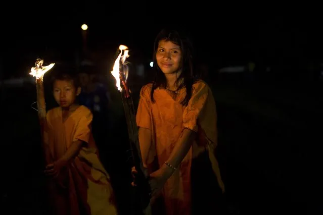 In this June 23, 2015 photo, Ashaninka Indian school children parade with torches during festivities celebrating the 44th anniversary of their village, in Otari Nativo, Pichari, Peru. The village is located in a valley near the Apurimac, Ene and Mantaro rivers in the world's largest coca growing region. (Photo by Rodrigo Abd/AP Photo)