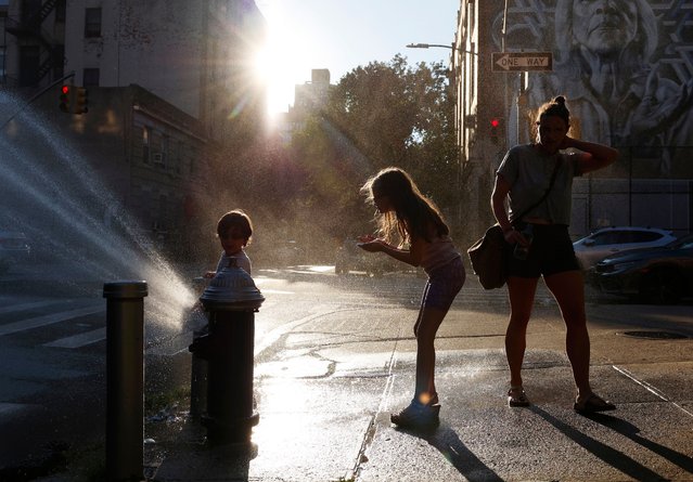 An adult and two children stop to cool off at the water from an open fire hydrant in hot and humid weather in New York City on Thursday, July 11, 2024. After dealing with extreme humidity and heat for the past few days the trip-state area got a break as humidity levels took a slight but noticeable drop. (Photo by John Angelillo/UPI/Rex Features/Shutterstock)