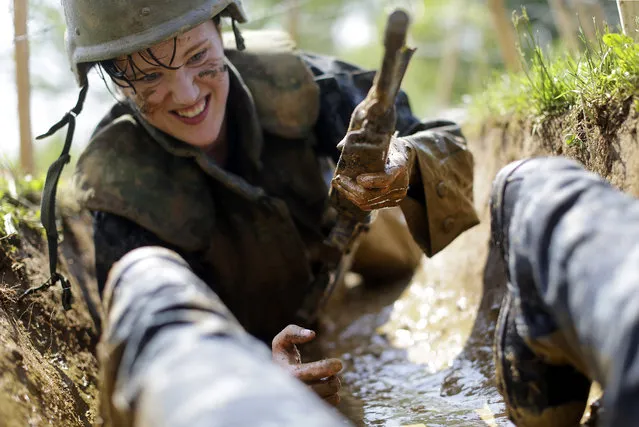 A freshman midshipman, known as a plebe, crawls through a muddy trench underneath barbed wire during Sea Trials, a day of physical and mental challenges that caps off the freshman year at the U.S. Naval Academy, in Annapolis, Md., Tuesday, May 13, 2014. (Photo by Patrick Semansky/AP Photo)