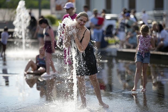 A young woman cools off in a fountain at VDNKh (The Exhibition of Achievements of National Economy) enjoying the warm weather, in Moscow, Russia, on Sunday, June 30, 2024. Warm weather has settled in Moscow with a temperature of 31 Celsius, (87,8 Fahrenheit) and will increase in the coming days. (Photo by Alexander Zemlianichenko/AP Photo)