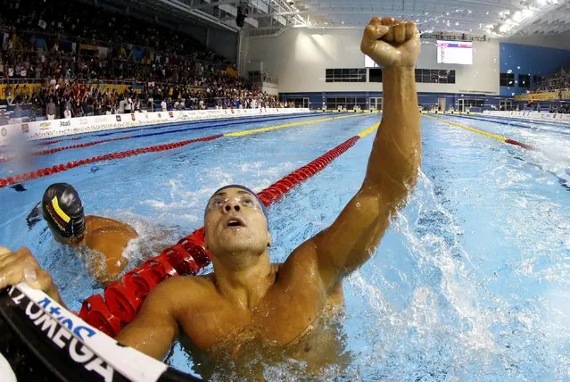 In a photo taken with a fisheye lens, Brazil's Felipe Franca Da Silva celebrates after winning the gold medal in the men's 100m breaststroke final at the Pan Am Games, Friday, July 17, 2015, in Toronto. (Photo by Julio Cortez/AP Photo)