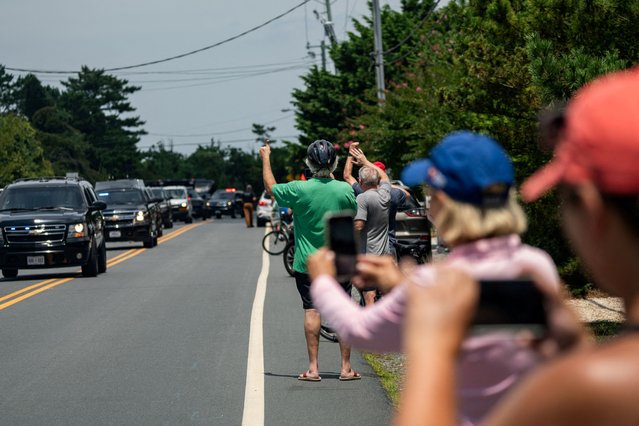 People gather as the motorcade of U.S. President Joe Biden passes through, in Rehoboth Beach, Delaware on July 23, 2024. (Photo by Jeenah Moon/Reuters)