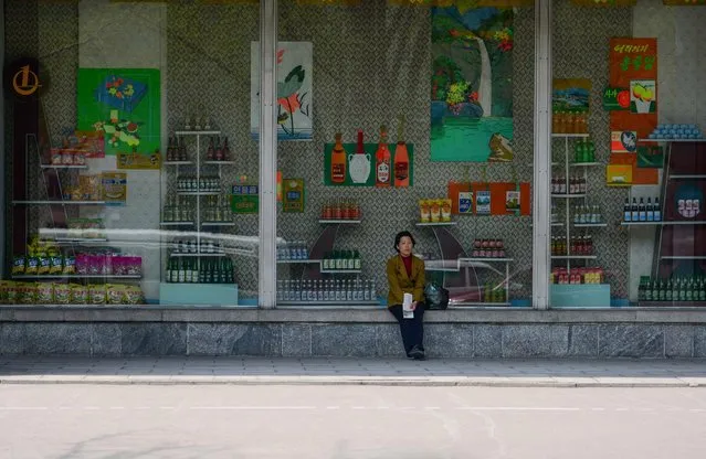 A woman sits on the ledge of a “store front” which turned out to be completely empty beyond the display. (Photo by Gavin John/Mediadrumworld.com)