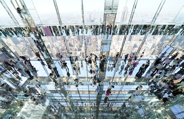 People look out at the city among 30,375 square feet of mirrors at SUMMIT One Vanderbilt in New York on May 22, 2024. The Parade of Ships is seen from SUMMIT One Vanderbilt in NYC as part of the Fleet Week Celebration events. (Photo by Timothy A. Clary/AFP Photo)