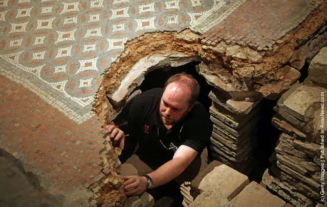 David Rawcliffe, house and monument steward at the National Trust's Chedworth Roman Villa cleans a Roman mosiac in the new environmentally-controlled conservation shelter near Cirencester, England