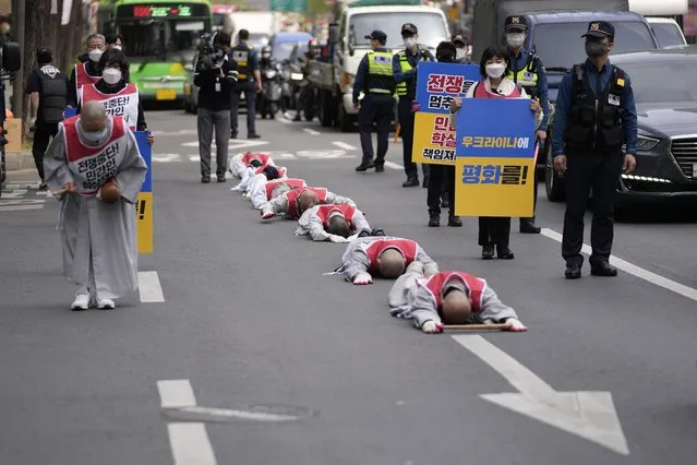 South Korean Buddhist monks, buddhists and members of civic groups bow which they prostrate themselves, on the road in a march as they move toward to Russian Embassy to wish for peace and stop the war in Ukraine, Tuesday, April 12, 2022, in downtown Seoul, South Korea. (Photo by Lee Jin-man/AP Photo)